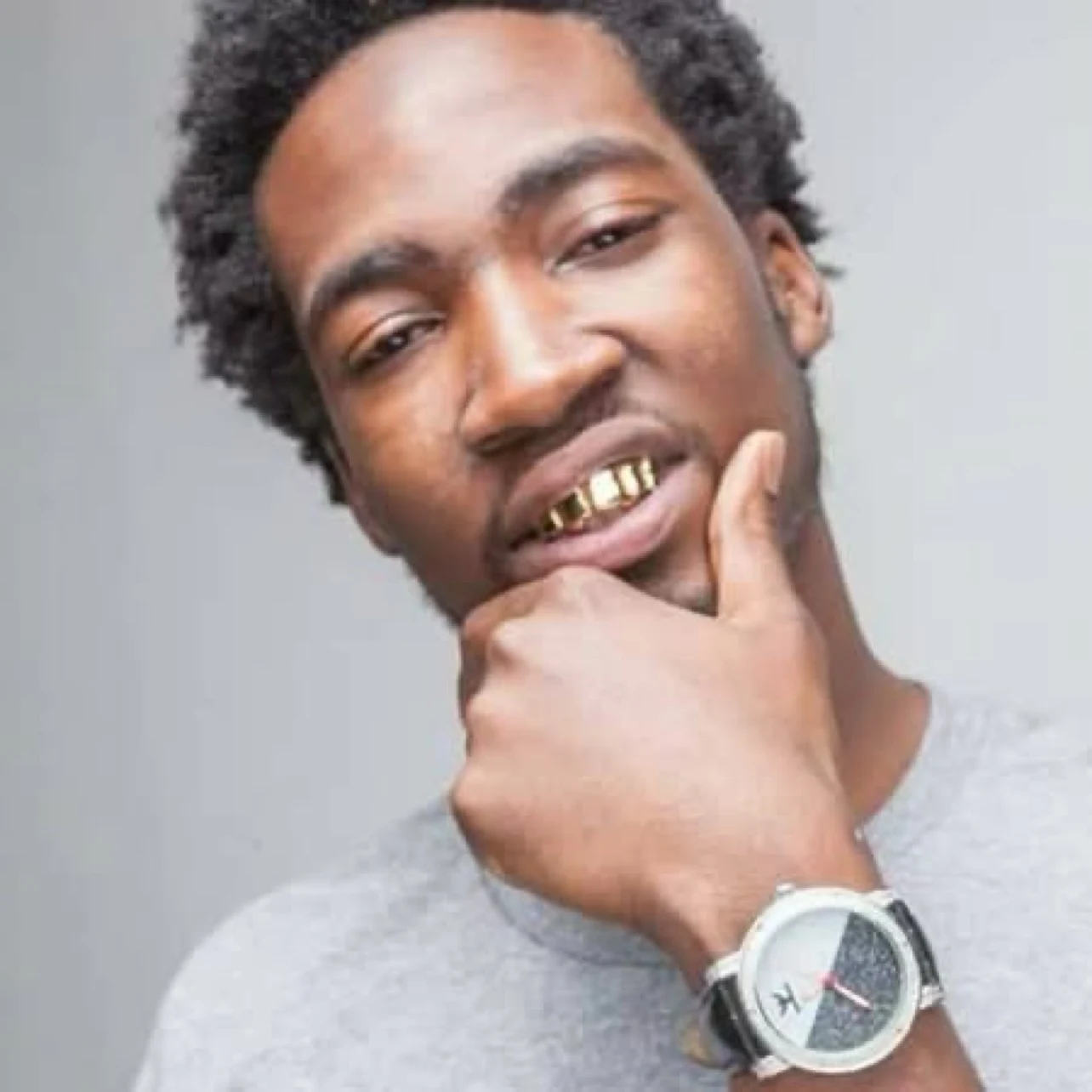 Keylo Da Beast wearing a gray shirt and gold grill in a studio portrait