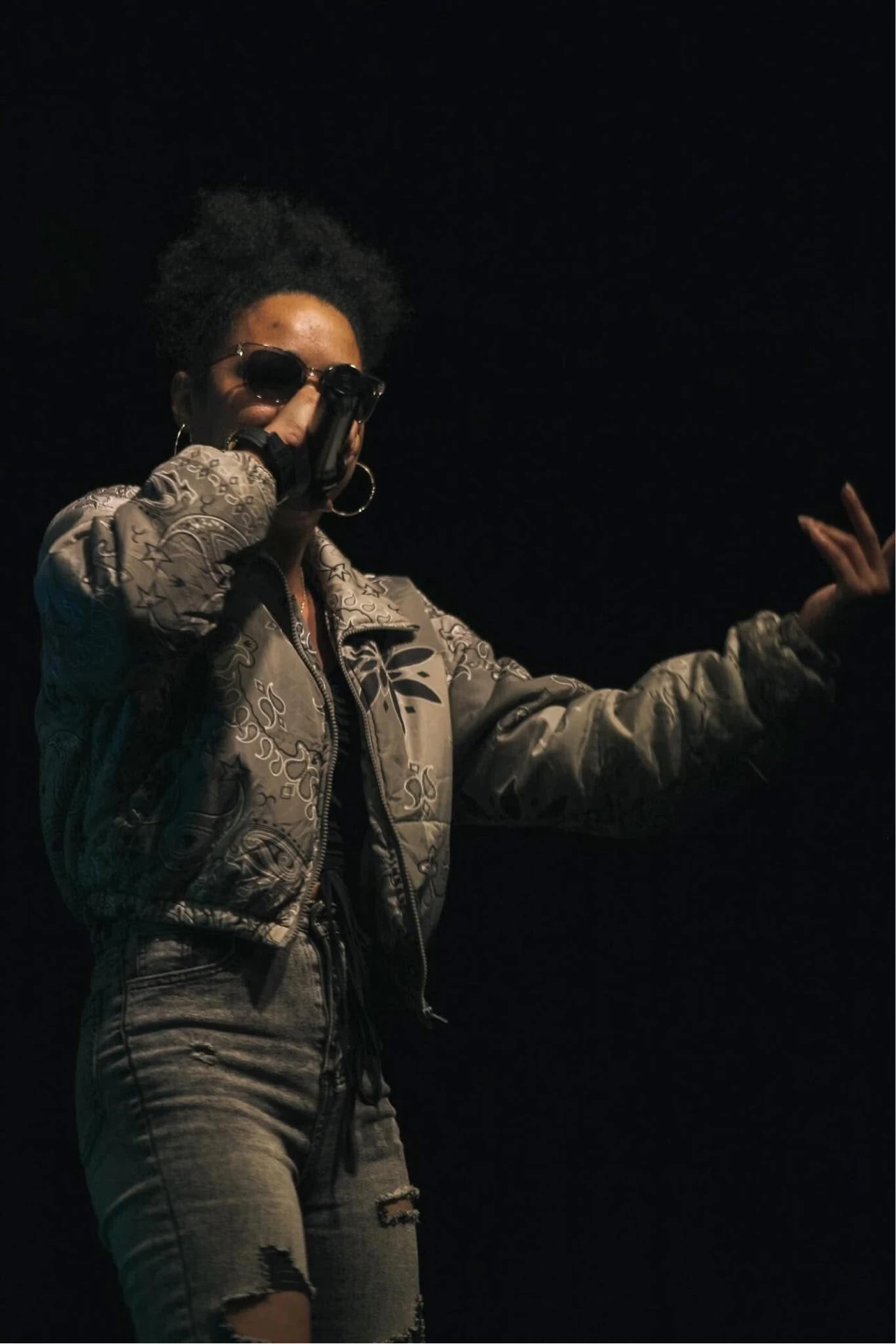 LeLe Montana performing on stage in sunglasses and a patterned jacket