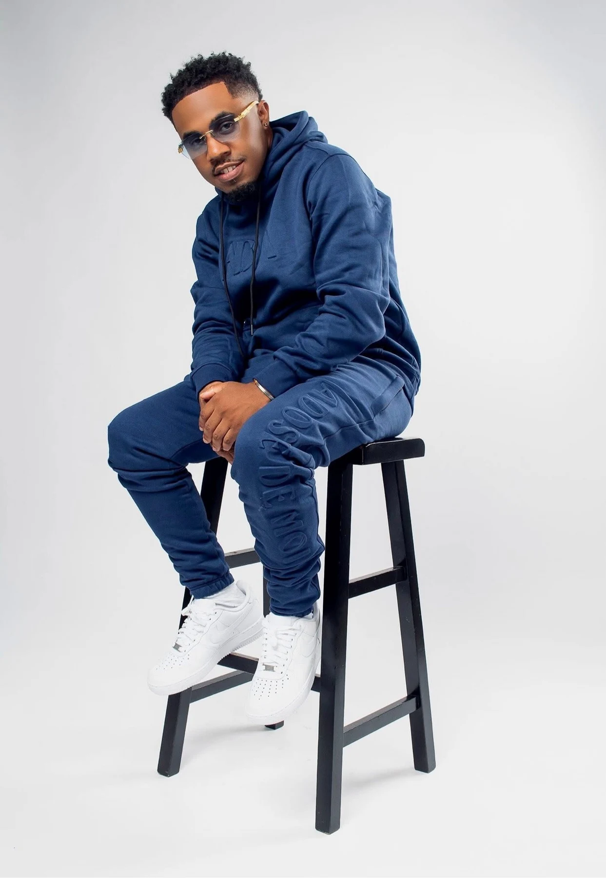 oNE Nuke seated on a stool in a navy sweatsuit